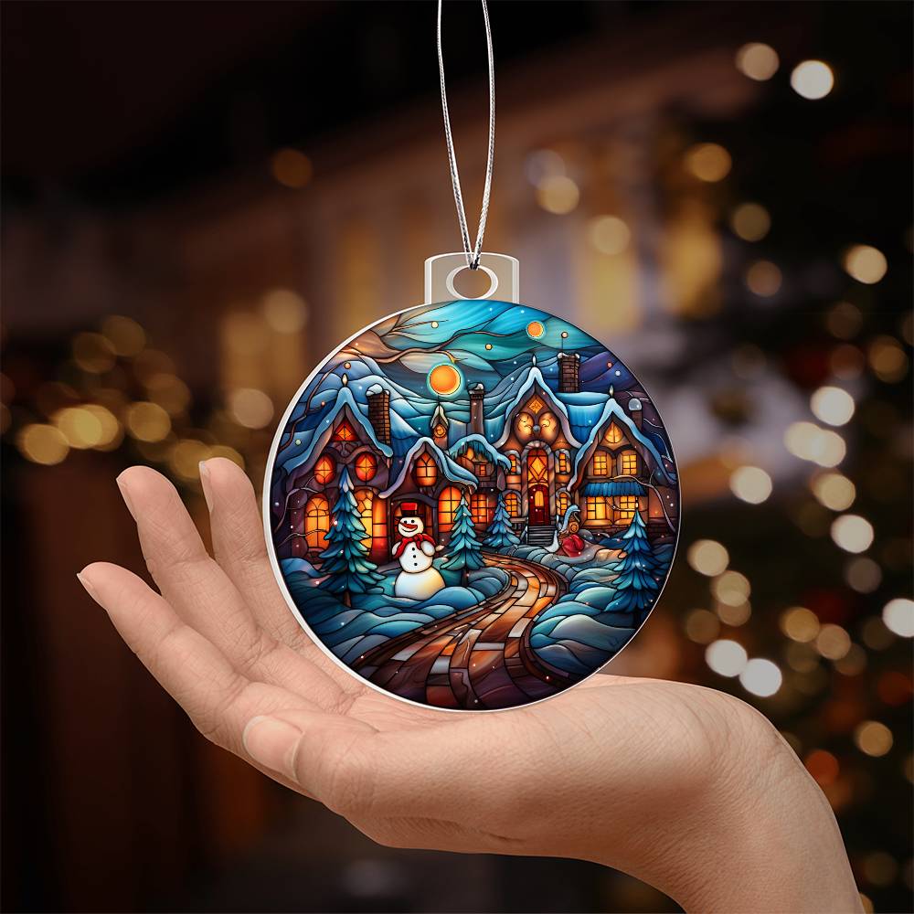 Hand holding Christmas acrylic ornament featuring a snowy night, cheerful snowman, and glowing winter village scene.