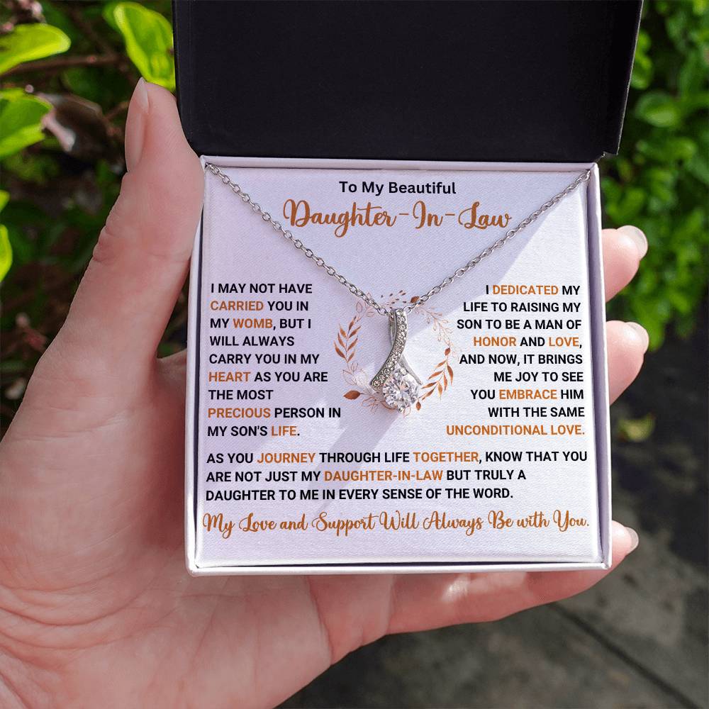 Woman holding Alluring Beauty necklace gift box with heartfelt message for daughter-in-law