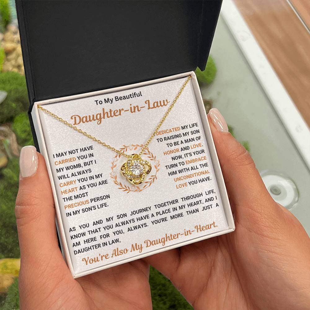 Woman holding necklace gift box with "To My Beautiful Daughter In Law" message, featuring a love knot pendant with cubic zirconia crystals.