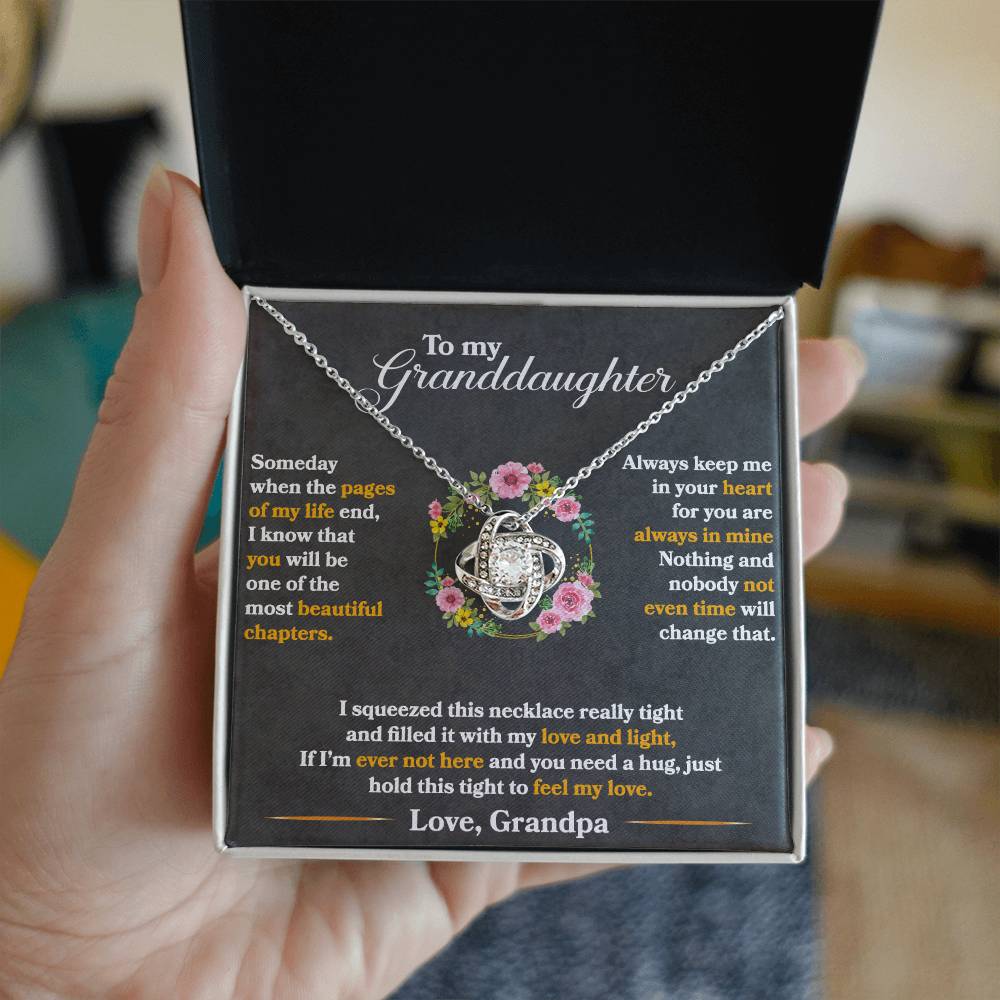 Hand holding a Love Knot Necklace gift box with a heartfelt message from Grandpa to Granddaughter, featuring cubic zirconia crystals.