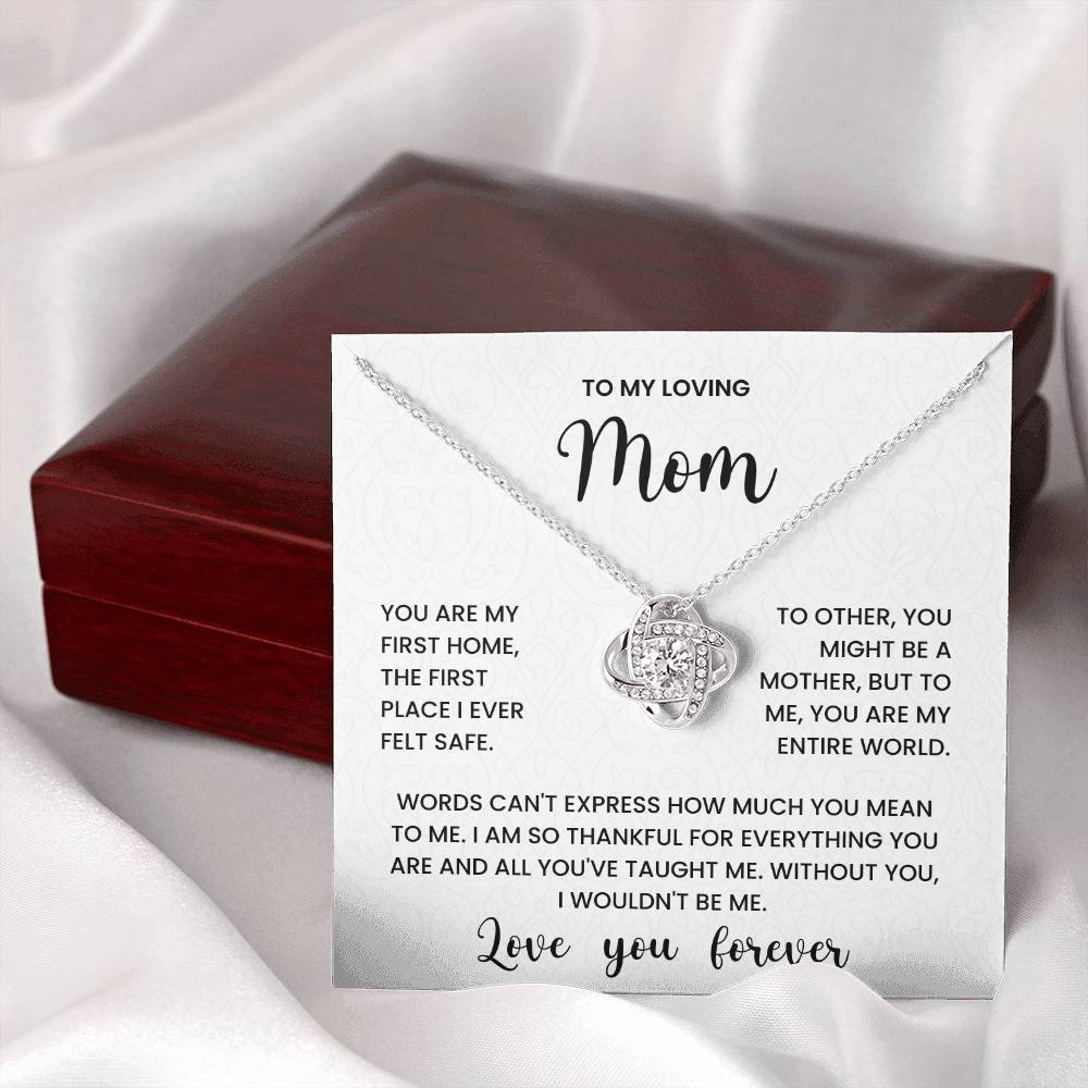 Love Knot Necklace for mom with heartfelt message on display card, placed in front of red jewelry box on white fabric