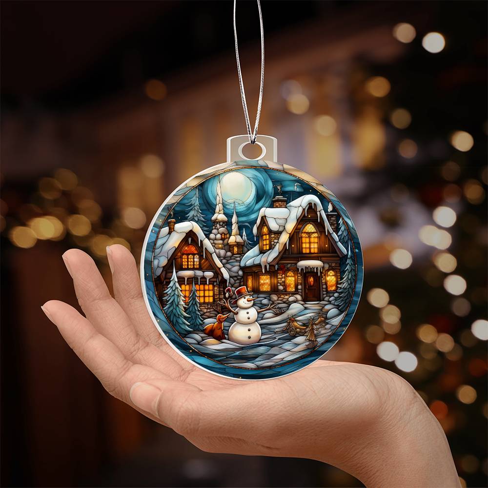 Hand holding a Snowy Cottage Christmas Charm ornament with cozy cottages and a snowman against a moonlit winter background.