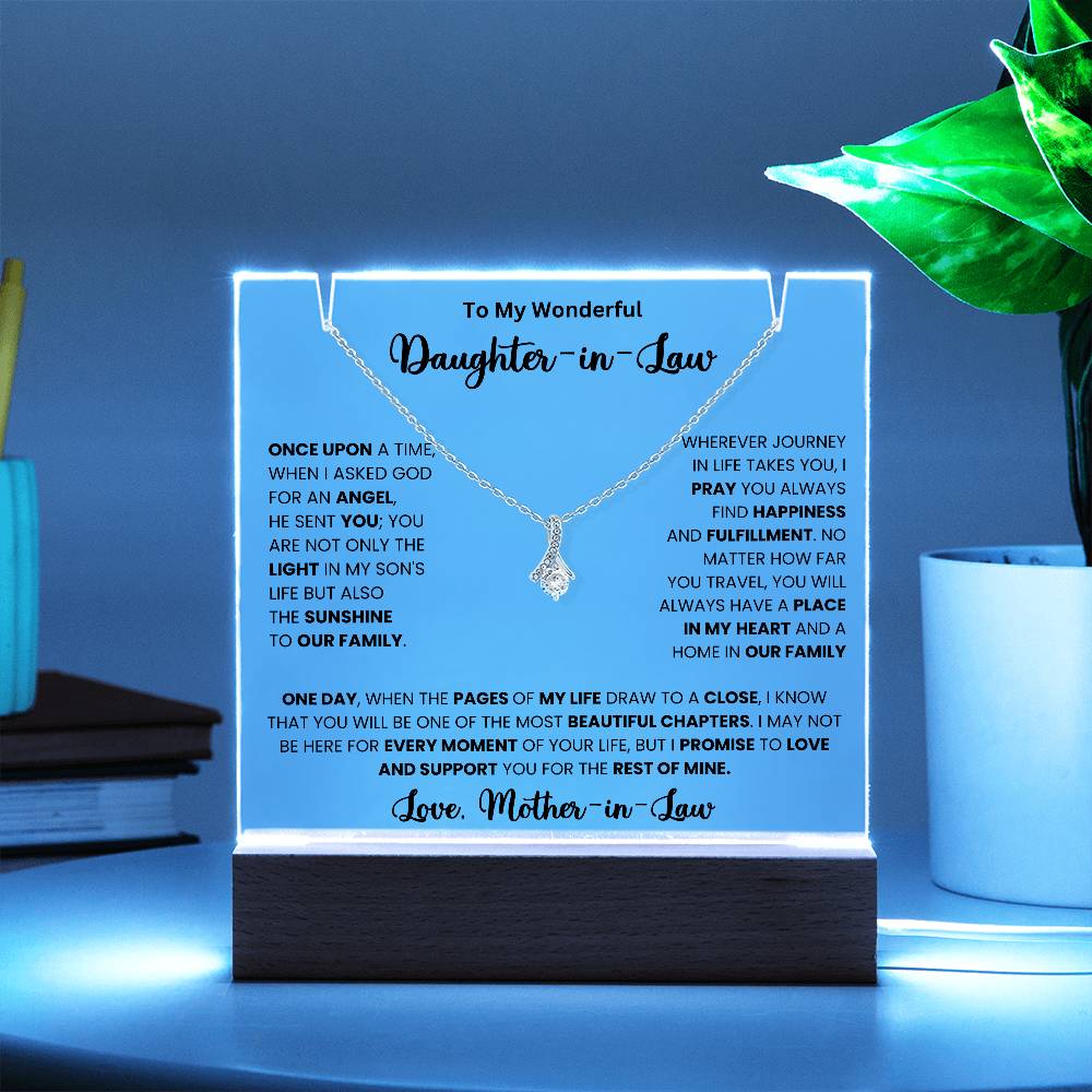 Keepsake acrylic necklace for daughter-in-law with heartfelt message from mother-in-law, displayed with blue background and plant.